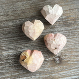 Four heart-shaped stone objects on a wooden surface