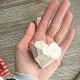 Hand holding a white stone against a wooden surface