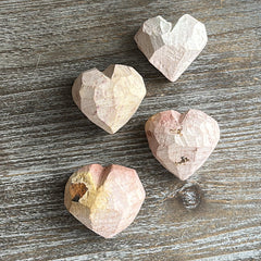 Four heart-shaped stone objects on a wooden surface